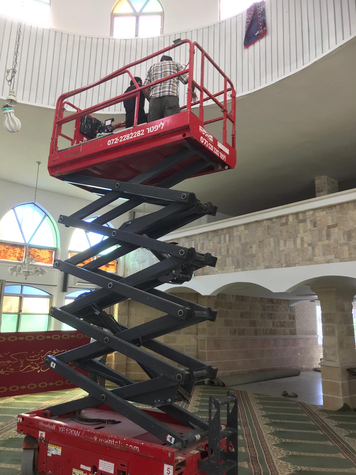 במת הרמה אדומה ניצבת בתוך אולם עם שני אנשים על הרציף המוגבה.